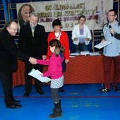 Najmłodsza uczestniczka szachowych rozgrywek z Gąbinie, 8-letnia Katarzyna Milczarek z Gąbina, odbiera gratulacje od ks. kan. Józefa Szczecińskiego