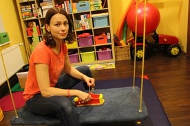 Sylwia Gątarek pokazuje pomoce terapeutyczne. Za pomocą tego drewnianego buta, dzieci uczą się koordynacji ruchów.